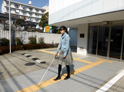 視覚障害者が点字ブロックの上を歩いている写真